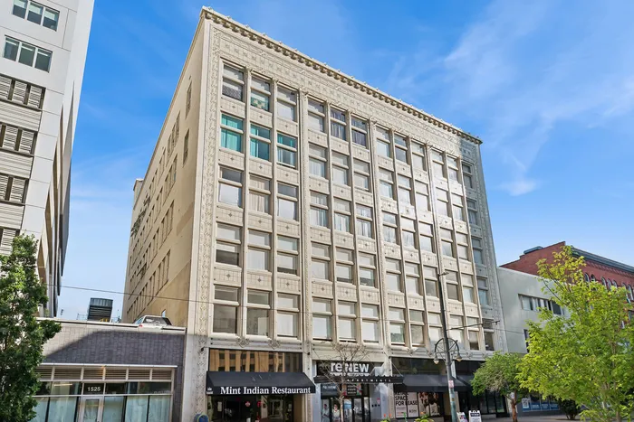 Charming urban apartment building with elegant architecture, featuring large windows and convenient ground-level retail space, perfect for city living.