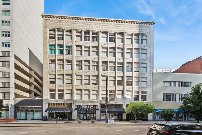 Impressive urban apartment building with classic architecture and vibrant street-level shops, perfect for city living.