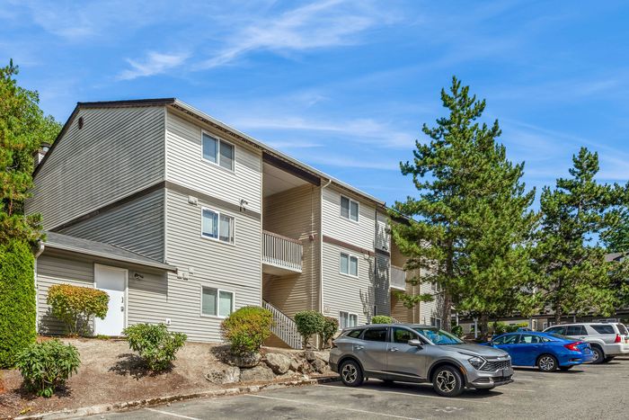 Charming apartment complex surrounded by lush greenery, featuring modern design and ample parking.