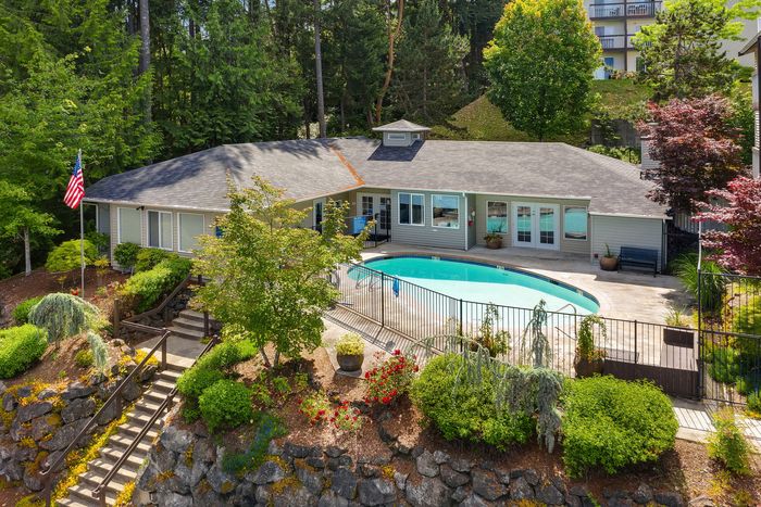 Charming single-story home surrounded by lush greenery with a sparkling oval swimming pool, offering a serene retreat in the heart of nature.