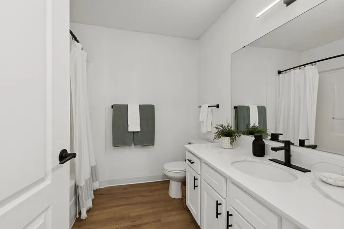 Elegant bathroom with sleek white countertops, modern fixtures, and warm wood flooring.