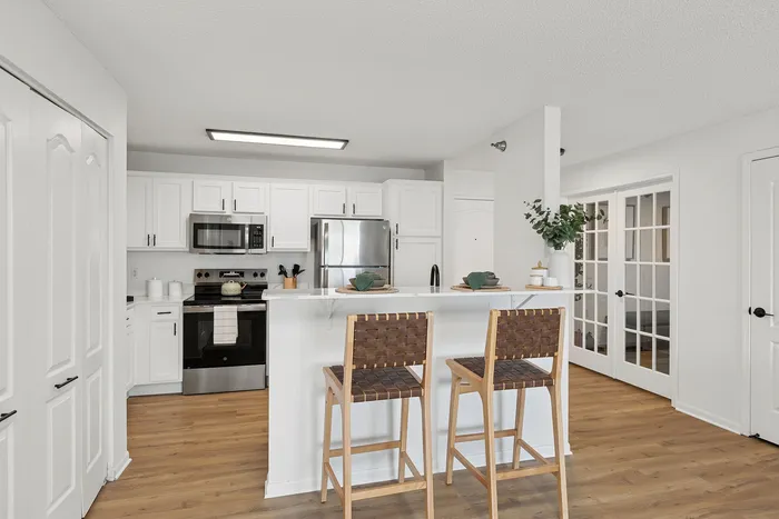 Modern kitchen with sleek white cabinetry, stainless steel appliances, and bar seating for a stylish, functional space.