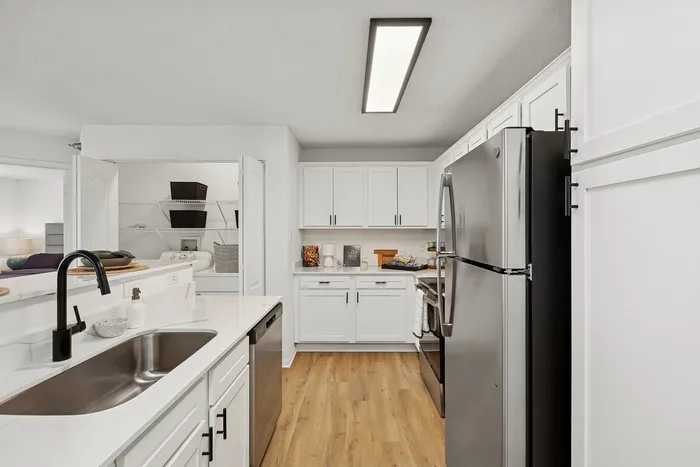 Modern kitchen with sleek stainless steel appliances, elegant white cabinets, and natural wood flooring, providing a stylish and functional cooking space.
