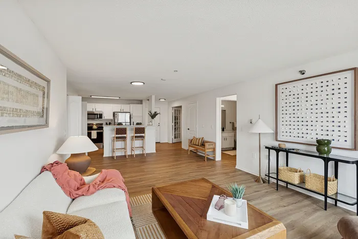 Bright and inviting living area with modern decor, cozy seating, and a stylish kitchen overlooking an open space.