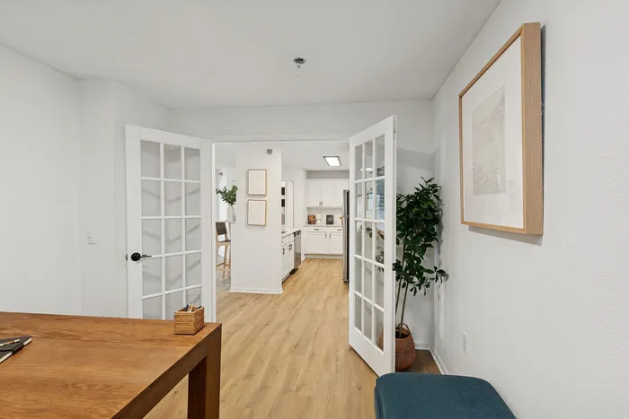 Inviting apartment entrance featuring elegant glass double doors, warm wooden floors, and stylish decor.