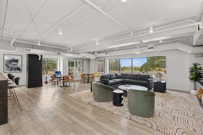 Modern living space with expansive windows, stylish furniture, and natural lighting, featuring a chic lounge area and elegant dining setup.