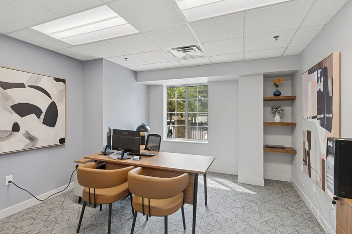 Bright, modern office space featuring sleek decor, stylish artwork, and a large window with natural light.
