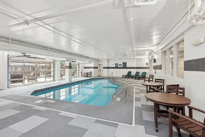 Bright indoor pool area with lounge chairs and seating, complemented by natural light and modern design.