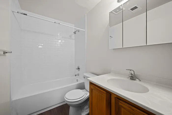 Modern bathroom featuring a pristine white bathtub, elegant vanity with wood cabinetry, and sleek fixtures.