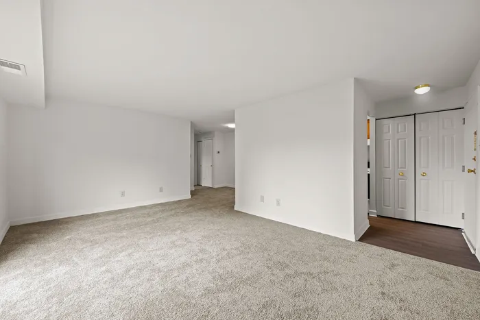 Spacious and bright living room with plush carpeting, neutral walls, and elegant double doors.