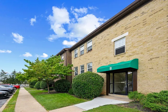 Inviting apartment entrance with green awning and well-maintained landscaping, perfect for a vibrant community living experience.