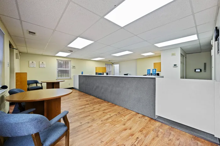 Welcoming office reception area with a modern design, featuring a spacious front desk, polished wood flooring, and comfortable seating.