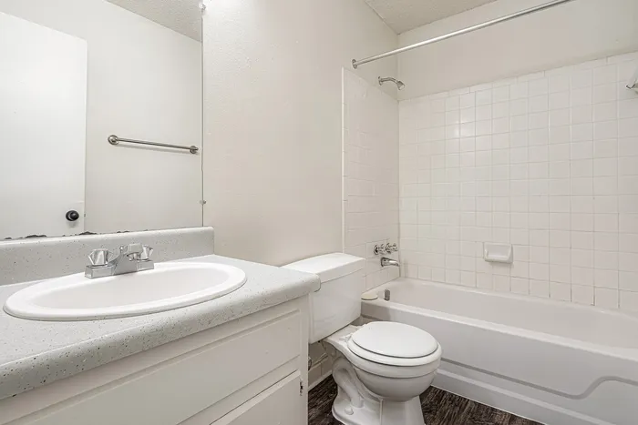Bright and elegant bathroom featuring a clean white vanity, modern fixtures, and a pristine bathtub with tiled walls.