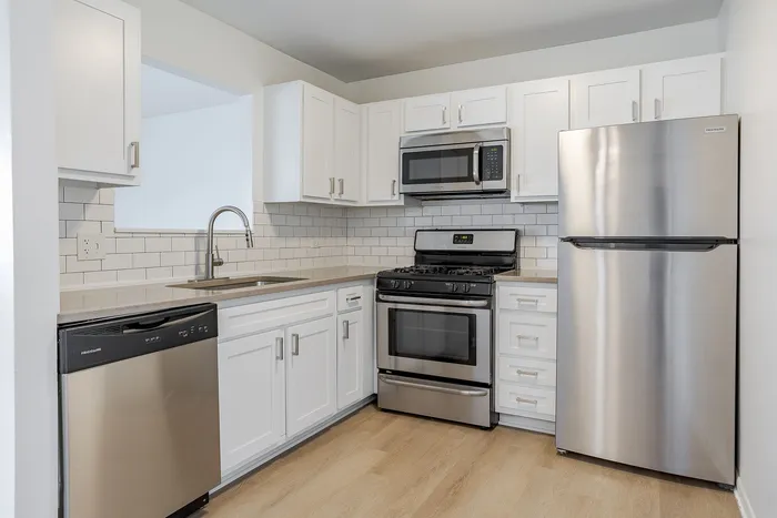 Modern kitchen with sleek stainless steel appliances, white cabinetry, and a stylish subway tile backsplash.