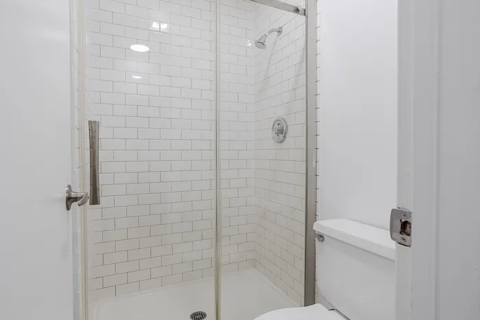Modern bathroom featuring a sleek glass shower door and pristine white subway tile, offering a clean and sophisticated style.