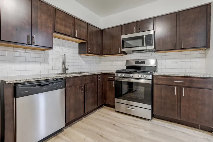Modern kitchen with sleek stainless steel appliances, elegant dark wood cabinets, and a stylish white subway tile backsplash.