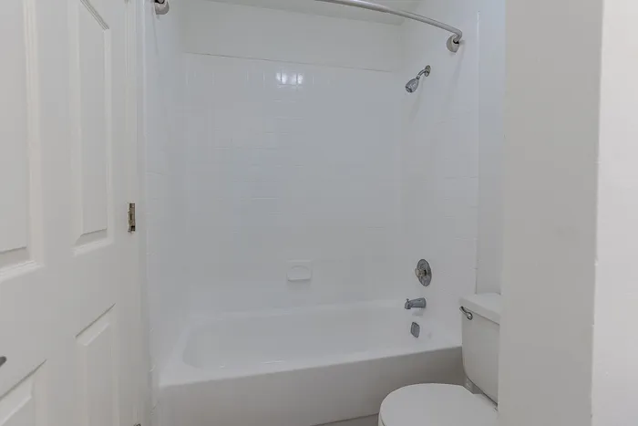 Pristine white bathroom featuring a modern bathtub and shower combination with sleek fixtures.