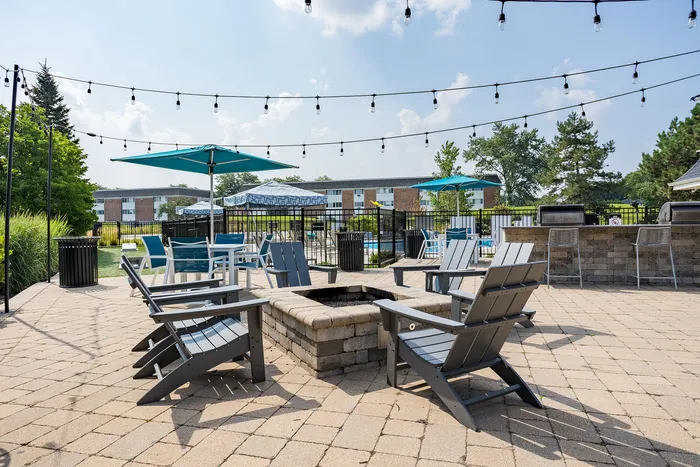 Inviting outdoor patio featuring cozy seating around a brick fire pit, complemented by string lights and colorful umbrellas, perfect for relaxation and entertaining.