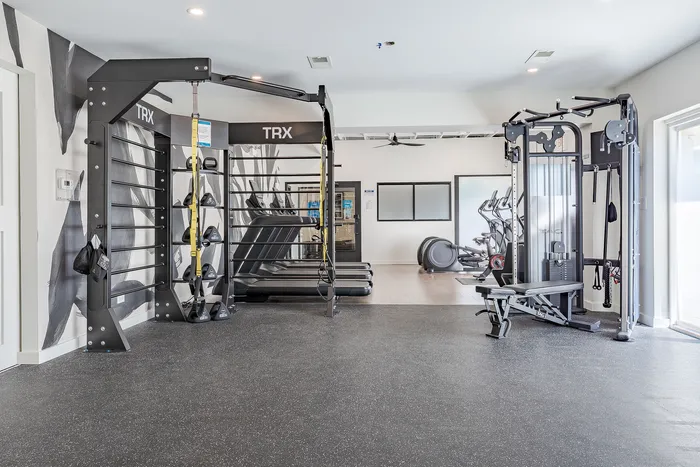 State-of-the-art gym featuring TRX equipment, treadmills, and modern fitness machines in a bright, spacious setting.