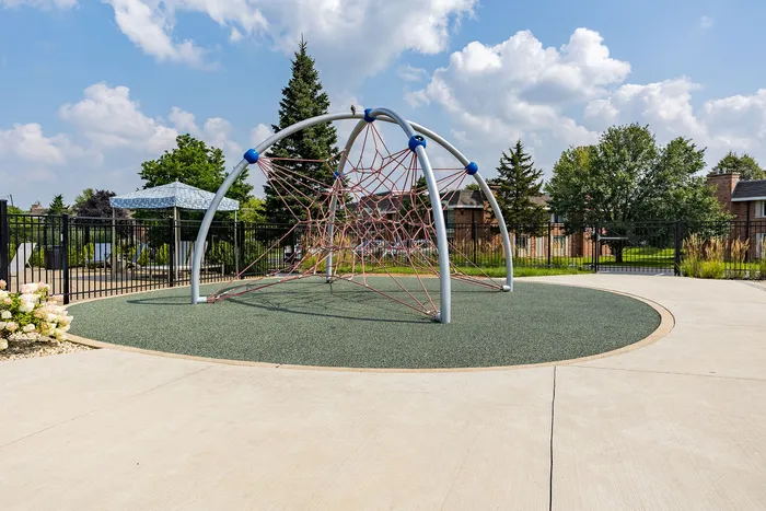 Inviting outdoor playground featuring a modern climbing dome surrounded by lush greenery and a vibrant community setting.