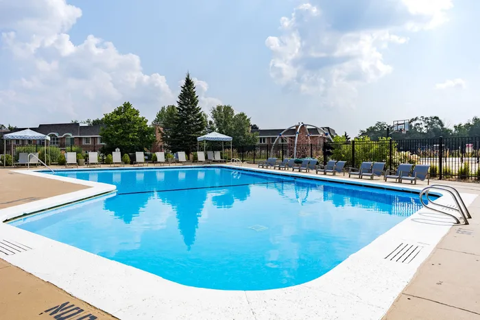 Inviting outdoor pool with lounge chairs and elegant umbrellas, perfect for relaxation in a lush, sunlit environment.