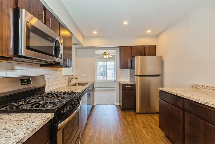 Elegant modern kitchen with stainless steel appliances, rich wood cabinets, and granite countertops, exuding a warm and inviting atmosphere.