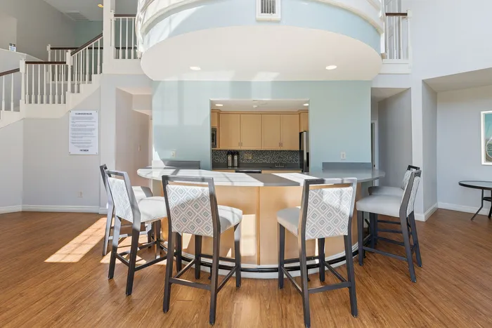 Elegant open kitchen area with a modern circular bar and stylish high chairs, complemented by hardwood floors and inviting natural light.