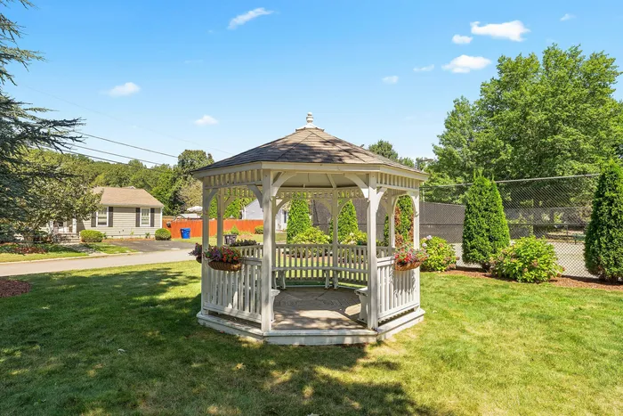 Charming garden gazebo surrounded by lush greenery and vibrant flower arrangements, perfect for relaxation in a serene outdoor setting.