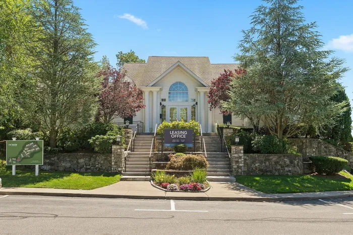 Charming leasing office surrounded by lush greenery, featuring a welcoming entrance and beautifully landscaped gardens.