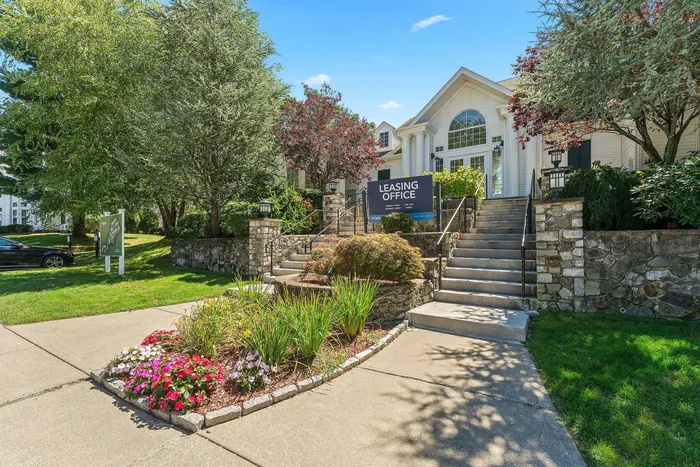 Inviting leasing office surrounded by lush greenery and vibrant flowers, offering a warm welcome.
