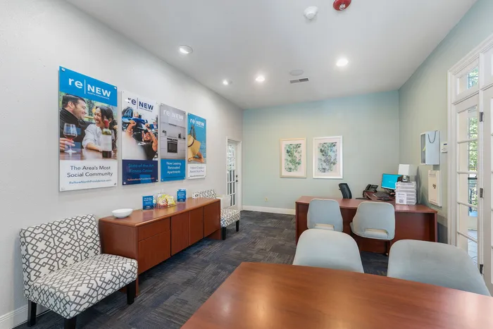 Bright and inviting leasing office featuring modern decor, promotional posters, and comfortable seating.