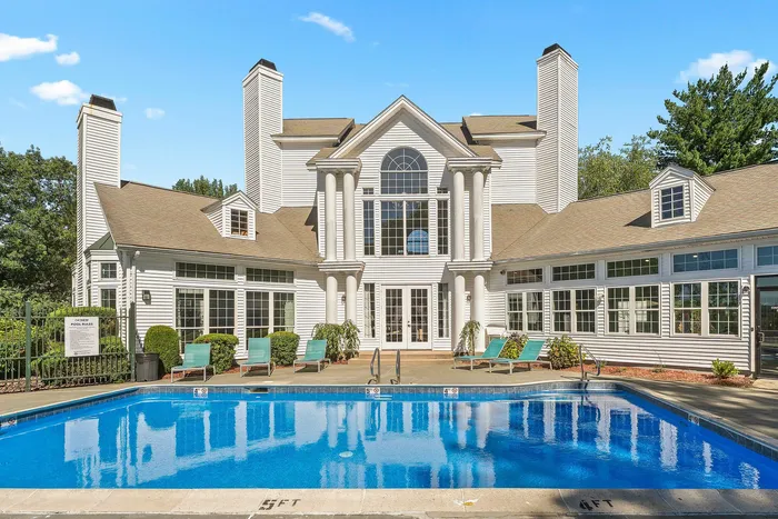 Elegant residential building with a classic facade, large windows, and inviting pool area, perfect for relaxing and entertaining.