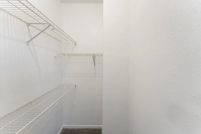 Bright and spacious walk-in closet with customizable shelving, perfect for ample storage solutions.