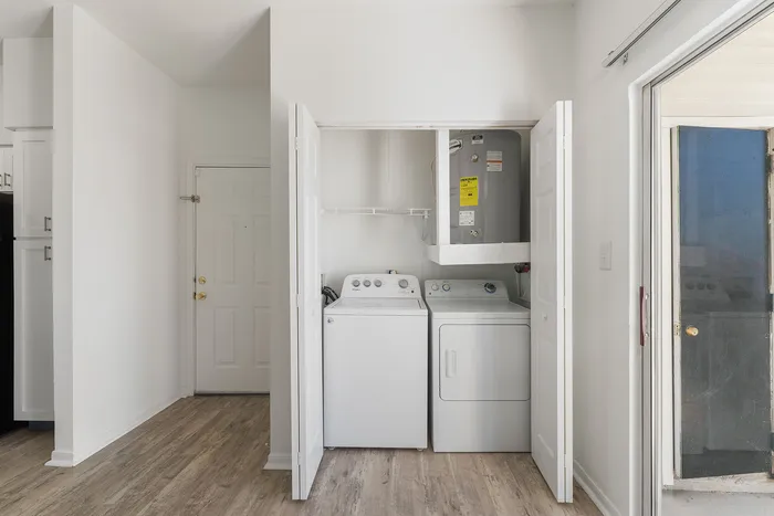 Bright, inviting laundry area with modern washer and dryer, wood-style flooring, and ample storage space.