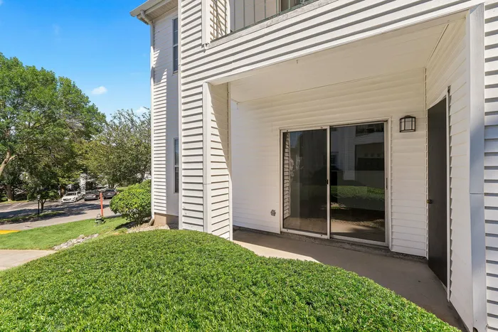 Charming patio view with sliding glass doors, lush green lawns, and bright exterior showcasing inviting outdoor space.