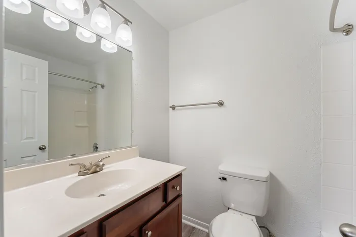Bright, stylish bathroom featuring a spacious mirror, elegant light fixtures, and modern fixtures in a serene setting.
