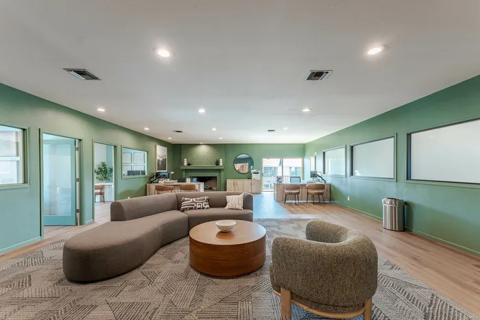 Inviting modern lounge with chic seating, stylish decor, and green-themed walls, perfect for relaxation and gatherings.