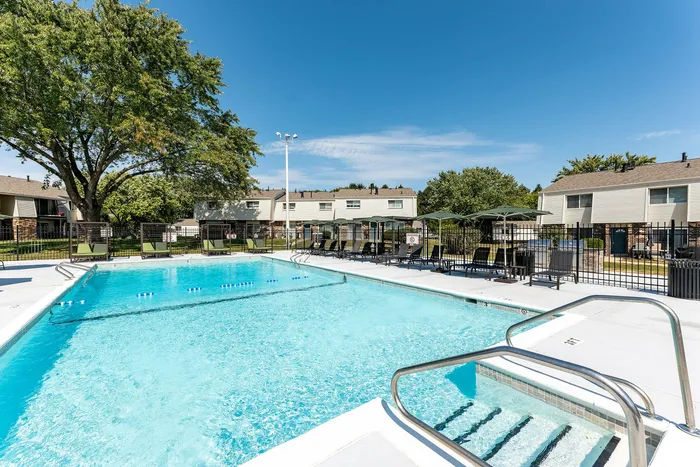 Inviting outdoor pool at a modern apartment complex featuring lush green surroundings and comfortable seating areas.