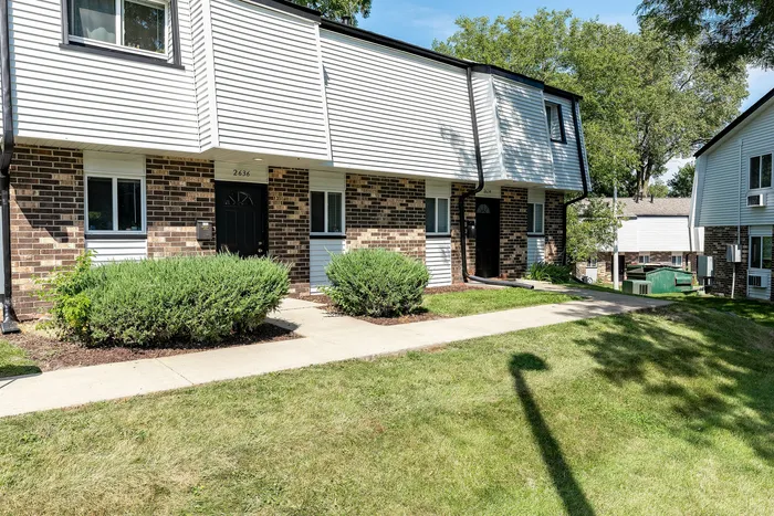 Charming townhouse exterior with modern brick and siding finish, featuring well-maintained lawns and inviting entryways.