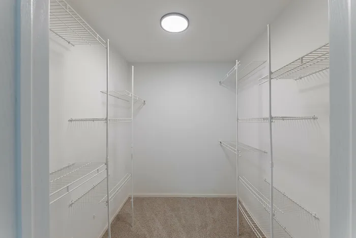 Spacious and well-lit walk-in closet with sleek wire shelving, perfect for organized living.