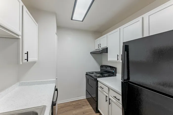 Contemporary kitchen with sleek black appliances, white cabinetry, and elegant countertops.