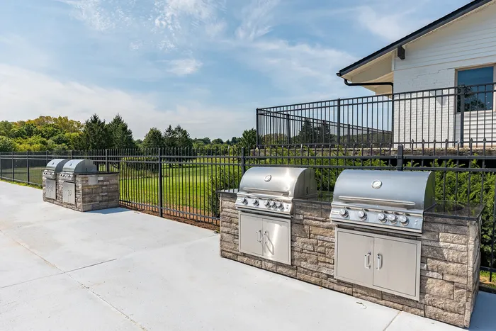 Inviting outdoor grilling station with sleek stainless steel BBQs surrounded by lush greenery, perfect for entertaining.