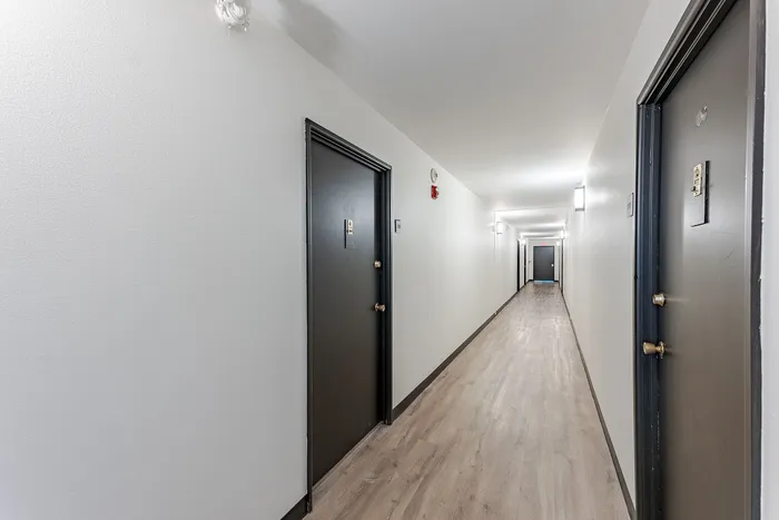 Modern apartment hallway with sleek doors and bright lighting creating an inviting atmosphere.