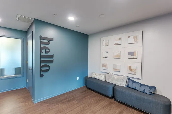 Modern entryway with teal accent wall, welcoming decor, and cozy seating, creating an inviting atmosphere.