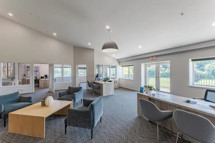 Bright and modern office lobby with elegant furnishings, large windows, and scenic outdoor views.