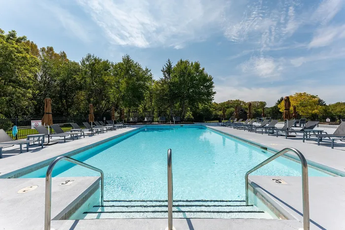 Inviting outdoor pool with crystal-clear water, surrounded by lush greenery and comfortable lounge chairs.