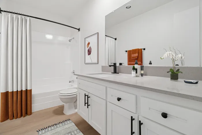 Elegant bathroom with a modern white vanity, sleek black fixtures, and vibrant orange accents, creating a serene and stylish ambiance.