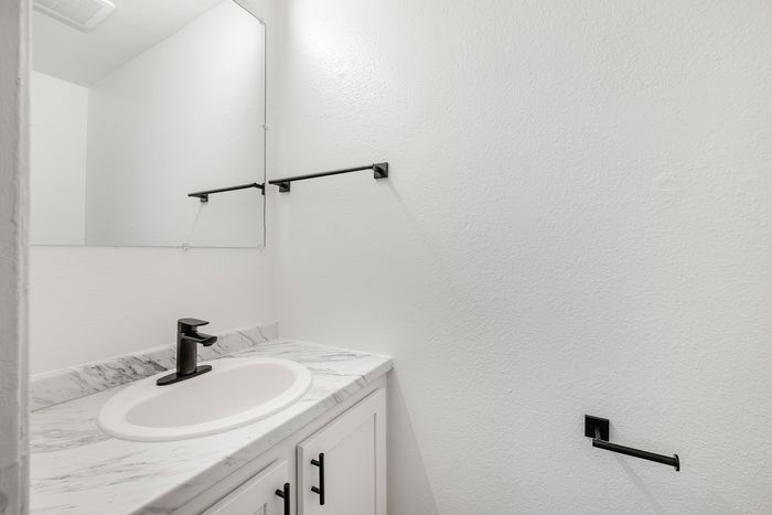 Modern bathroom with elegant marble countertop, sleek black fixtures, and a large mirror enhancing the space.
