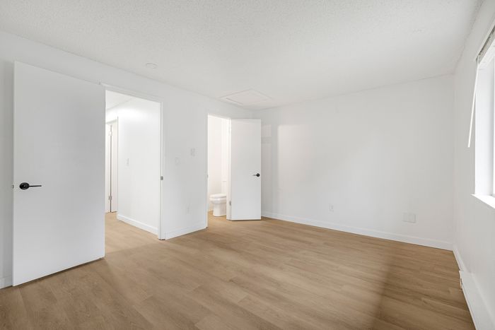 Bright and spacious room with sleek wooden flooring and contemporary white doors, perfect for modern living.