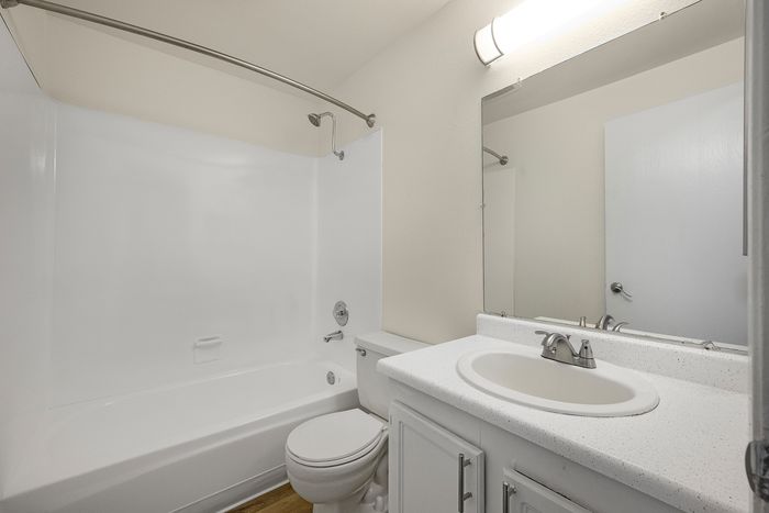 Modern bathroom featuring a sleek white tub, elegant vanity with a spacious counter, and ambient lighting for a serene atmosphere.